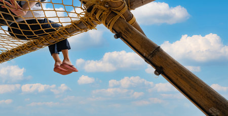 Summer travel at the beach with blue sky and white clouds. Summer vibes. Summer vacations. Relax on vacations. Woman with pink flipflop sit on net rope with enjoy and relax mood on holiday at resort.の写真素材
