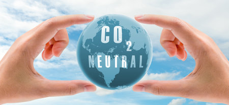 Carbon neutral concept. Hand holding CO2 neutral in globe map on blue sky and white clouds background. Environment day. Carbon neutral web banner. Environment issue. Global carbon neutrality concept.の写真素材