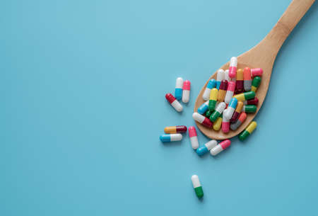 Antibiotic capsule pills on spoon and blue background. Antibiotic drug resistance. Pharmaceutics. Medical health care. Prescription drugs. Drug use problems. Dose of medicine. Pharmaceutical care.の写真素材
