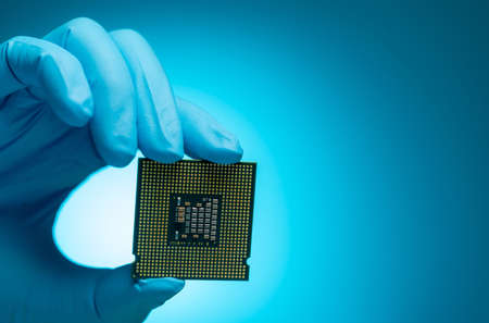 Electronic engineer hand holding computer chip blue background. Chipset of electronic circuit board for PC motherboard. CPU chip. Electronic components. Computer hardware. Computer processor chip.の写真素材