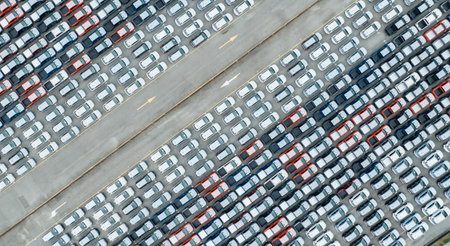 Aerial view of new cars stock at factory parking lot. Above view many cars parked in a row....