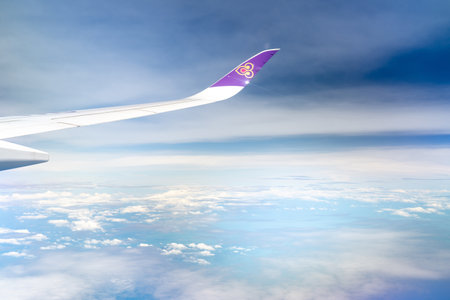 BANGKOK, THAILAND-OCTOBER 19, 2019 : Plane wing of Thai Airways Airlines. Passenger plane. Wing of plane over white fluffy clouds. Airplane flying on blue sky. Scenic view from airplane window.のeditorial素材
