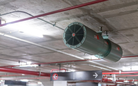 Jet fan at underground parking area. Ventilation fan in the parking lot. Air flow system. Ventilation system in underground car parking lot at commercial building. Duct fan air ventilation at mall.の写真素材