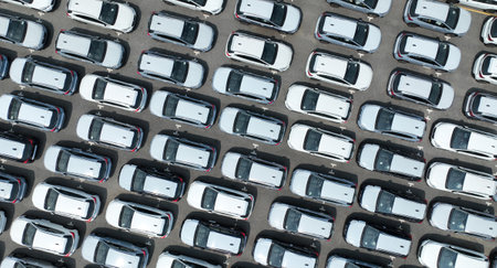 Aerial view of new cars stock at factory parking lot. Above view cars parked in a row. Automotive...