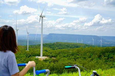 Wind farm with woman riding bike in foreground. Wind energy. Wind power. Sustainable, renewable...