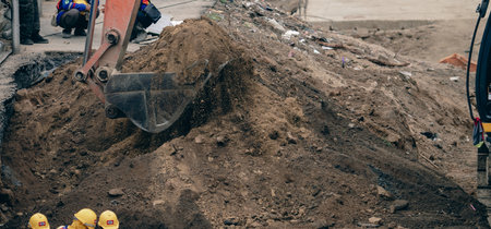 Backhoe working by digging soil at construction site. Bucket teeth of backhoe digging sand. Crawler excavator digging on soil. Excavating machine. Earthmoving machine. Excavation vehicle. Road repair.の写真素材