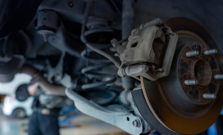 Car disc brake system. Car suspension in process of new tire replacement at garage workshop. Car...