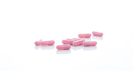 Pink capsule pills on white background. Pharmaceutical industry. Vitamins, minerals, and supplements...
