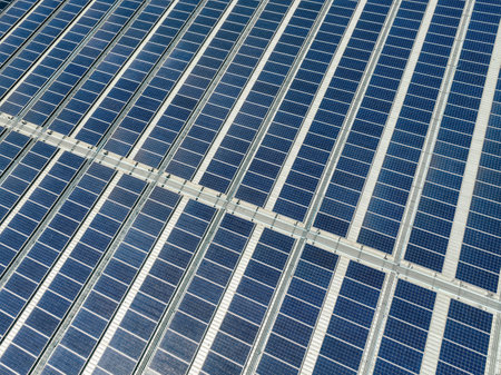 Solar panels on roof of industrial plant. Solar energy for factory or warehouse building. Commercial solar. Industrial photovoltaic panels. Rooftop solar power. Green energy. Sustainable energy.の写真素材