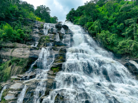 Beautiful waterfall with a lush green forest in the background. The water is flowing down the rocks and creating a beautiful scene. Sustainable waterfall in lush forest promoting water sustainability.の写真素材