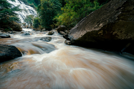 Beautiful waterfall with a lush green forest in the background. The water is flowing down the rocks and creating a beautiful scene. Sustainable waterfall in lush forest promoting water sustainability.の写真素材