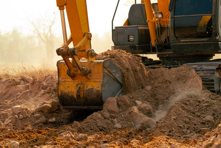 Backhoe working by digging soil at construction site. Crawler excavator digging on demolition site. Excavating machine. Earth moving machine. Excavation vehicle. Construction business.の写真素材