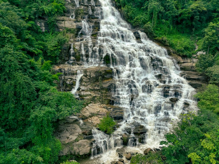 Aerial view of a waterfall in a lush tropical green forest in Doi Inthanon National Park, Chiang Mai, Thailand. This nature landscape showcases water sustainability and scenic travel destinations.の写真素材