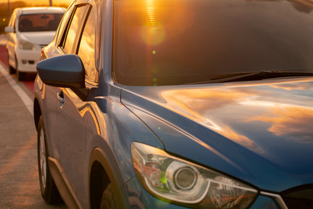 Luxury SUV with modern design parked on roadside at sunset. Front view of blue vehicle, symbolizing business success and eco-friendly technology. Electric vehicle. Sustainable travel. Summer road tripの写真素材
