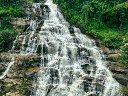 Aerial view of a waterfall in a lush tropical green forest in Doi Inthanon National Park, Chiang Mai, Thailand. This nature landscape showcases water sustainability and scenic travel destinations.の写真素材