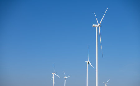 A group of wind turbines against blue sky, Wind energy. Wind power. Sustainable, renewable energy. Wind turbine generate electricity. Sustainable resources. Green technology for energy sustainability.の写真素材