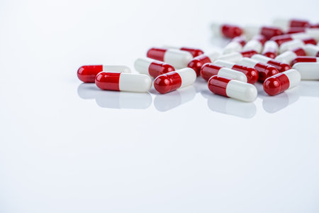 Red white capsules scattered on white background illustrate drug discovery journey from laboratory to market. Pharmaceutical innovation process and rigorous approval stages for new medications.の写真素材