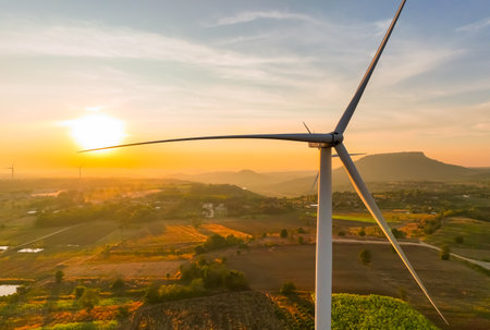 Wind farm field and sunset sky. Wind power. Sustainable, renewable energy. Wind turbines generate electricity. Sustainable development. Green technology for energy sustainability. Eco-friendly energy.の写真素材
