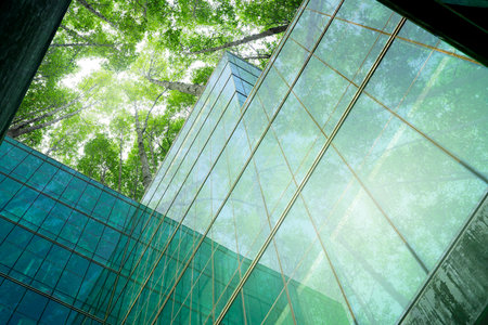 Eco-friendly building in modern city. Sustainable glass office building with trees for reducing CO2. Green architecture. Building with green environment. Sustainability corporate. Net zero emissions.の写真素材