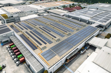Solar-powered warehouse facility with freight trucks at loading docks. Eco-friendly logistics and efficient cargo transportation. Solar panels and sustainable energy concept in distribution center.の写真素材