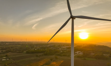 Wind farm field and sunset sky. Wind power. Sustainable, renewable energy. Wind turbines generate electricity. Sustainable development. Green technology for energy sustainability. Eco-friendly energy.の写真素材