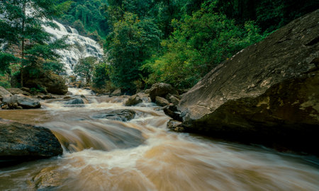 Beautiful waterfall with a lush green forest in the background. The water is flowing down the rocks and creating a beautiful scene. Sustainable waterfall in lush forest promoting water sustainability.の写真素材