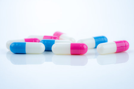 Blue and pink capsule pills spread on white background, showcasing pharmaceutical products, healthcare concepts, and the role of prescription medicine in advancing treatment and patient well-being.の写真素材
