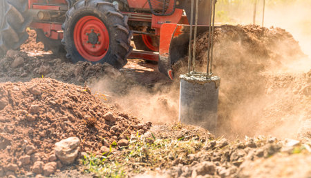 Construction tractor with specialized dozer blade pushing and grading soil at excavation site. Heavy machinery transforming raw land into prepared foundation for upcoming building development project.の写真素材