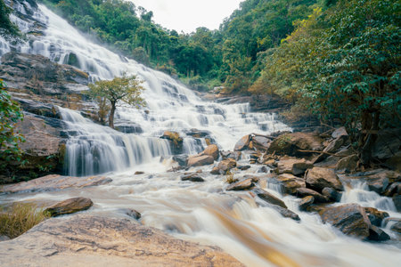 Beautiful waterfall with a lush green forest in the background. The water is flowing down the rocks and creating a beautiful scene. Sustainable waterfall in lush forest promoting water sustainability.の写真素材