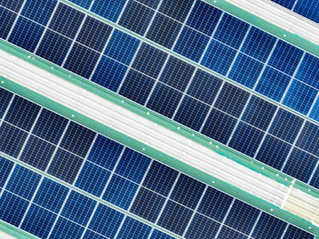 Rooftop solar panels on an industrial plant building. Ecofriendly electricity production, renewable energy efficiency, and sustainable technology for reducing carbon emissions in commercial settings.の写真素材