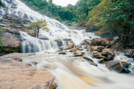 Beautiful waterfall with a lush green forest in the background. The water is flowing down the rocks and creating a beautiful scene. Sustainable waterfall in lush forest promoting water sustainability.の写真素材