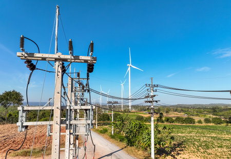 Electricity transmission tower under blue sky, collecting wind power from turbines in remote field....