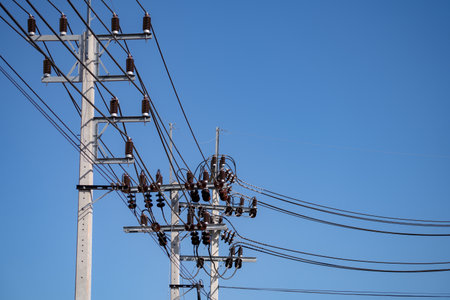High voltage transmission pole with electrical equipment including cables and insulators on concrete structure under clear blue sky showing modern power grid infrastructure in wind energy facilityの写真素材