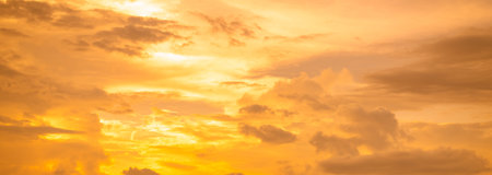 Golden sky texture background during sunset creating warm gradient colors perfect for luxury brand marketing and romantic design projects requiring elegant atmospheric natural lighting effectsの写真素材