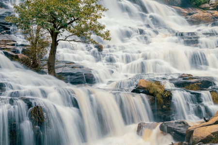 Beautiful waterfall with a lush green forest in the background. The water is flowing down the rocks and creating a beautiful scene. Sustainable waterfall in lush forest promoting water sustainability.の写真素材