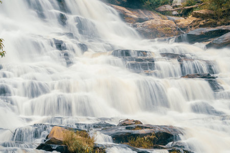 Beautiful waterfall with a lush green forest in the background. The water is flowing down the rocks...
