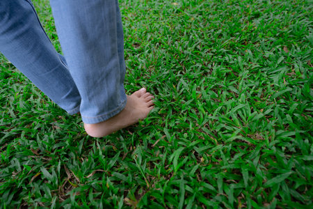 Close-up of barefoot person stepping on lush green grass lawn. Nature connection and natural healing...