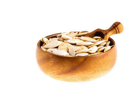 Pumpkin seeds in a wooden bowl isolated on whiteの写真素材