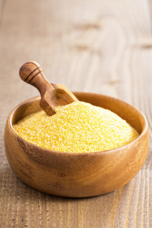 Raw polenta in a wooden bowl with a scoopの写真素材
