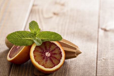 Blood oranges with fresh mint and wooden reamerの写真素材