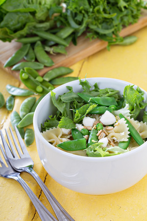 Pasta salad with farfalle, salad greens, peas and fetaの写真素材