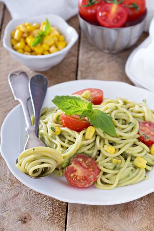 Vegan pasta with avocado sauce, tomatoes and cornの写真素材