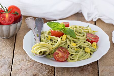 Vegan pasta with avocado sauce, tomatoes and cornの写真素材