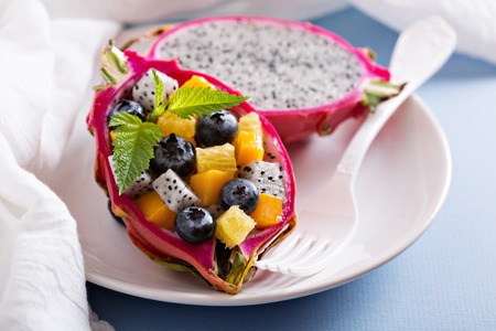 Tropical fruit salad served inside a dragon fruitの写真素材