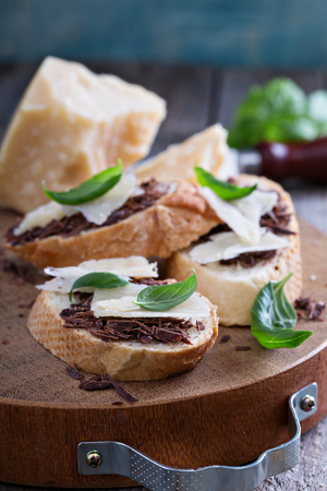 Chocolate and parmesan crostini with basil on a wooden boardの写真素材