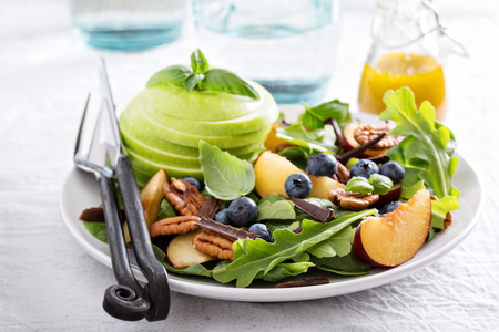 Fresh healthy salad with leafy greens, plums, nuts and appleの写真素材