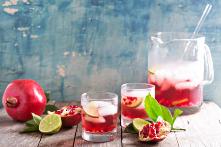 Pomegranate margarita cocktail with lime slices and iceの写真素材