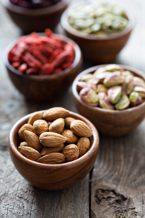 Variety of nuts and dried fruits in small wooden bowlsの写真素材