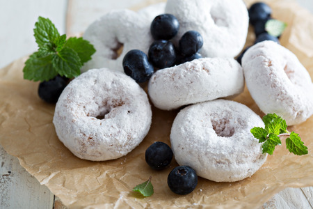 Powdered sugar donuts on parchment with blueberries and mintの写真素材