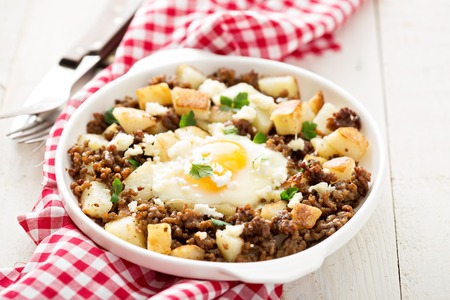 Potato hash with sausage and fried egg in a baking dishの写真素材